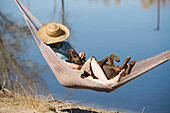 Young woman in a hat resting in hammock with her dog in Bishop, CA Bishop, California, USA
