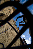 Peering up through a climbing rope at a belayer giving slack to a climber Terrebone, Oregon, USA