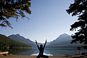 Silhouette of a woman practicing outdoor yoga at a remote lake in Glacier National Park Glacier National Park, Montana, USA