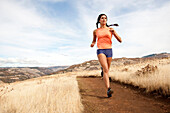 An athletic female jogs on a  dirt trail on an autumn day Hood River, Oregon, USA