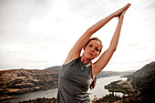 A female practicing yoga in the outdoors with the Columbia River Gorge in the distance Hood River, Oregon, USA