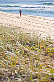 A woman runs along the soft sand at Sunshine Beach, Queensland, Australia Sunshine Coast, Queensland, Australia