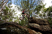 A Trials rider leaps onto a rock at Toohey Forest, Brisbane, Queensland, Australia Brisbane, Queensland, Australia