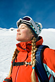A young woman soaks in the sun while skiing the backcountry of the Selkirk Mountains, Canada British Columbia, Canada