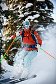 A woman backcountry skier catches air in the trees of the Selkirk Mountains, Canada British Columbia, Canada