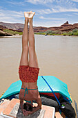 A woman doing a headstand on on the upper San Juan River, Mexican Hat, Utah Mexican Hat, Utah, USA