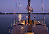A crew navigates a racing yacht home at dusk using high tech instruments Boothbay Harbor, Maine, USA