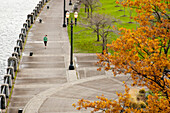 An athletic female in a green jacket jogging along the Portland, Oregon waterfront Portland, Oregon, USA