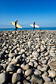 Two men walk the beach with surfboards under their arms on The Lost Coast, California Shelter Cove, California, USA