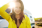 Female in her early 20's wearing a bright yellow hoodie poses in front of a vintage vehicle San Diego, California, USA