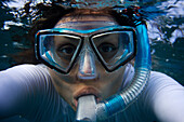 Young woman looks straight at the camera through a mask while snorkling in Maui, Hawaii Maui, Hawaii, USA