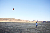 Young lady flies a kite in an open field Julian, California, USA