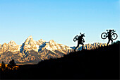 A man and a woman hike their bikes up a hill in Wyoming Jackson, Wyoming, USA
