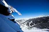 A snowboarder jumps off a cliff into powder in Colorado Vail, Colorado, USA