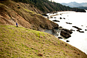 A woman hiking along a trail leading to the Pacific Ocean Cannon Beach, Oregon, USA