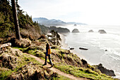 A woman hiking a secluded path along the coastline Cannon Beach, Oregon, USA