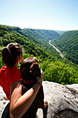 Woman and her dog take in the view from a high mountain cliff Fayetteville, West Virginia, USA