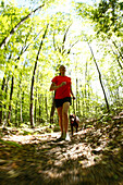 Woman trail running in a lush green forest with her dog Fayetteville, West Virginia, USA