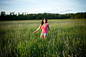 A girl twirls through tall grass on a sunny day in Idaho Sandpoint, Idaho, USA