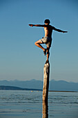 Man balances on log in British Columbia Tofino, British Columbia, Canada