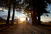 Young couple holding hands walk into the sunset in Idaho Sandpoint, Idaho, USA