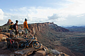 Three young men overlook a canyon after biking up the Amasa Back Trail, Moab, UT Moab, Utah, USA