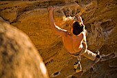 A young man rock climbs a boulder problem in Santa Barbara, CA Santa Barbara, California, USA
