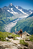 Hikers trek up a hill as the majesty of the Alps towers in the background Mont Blanc, France