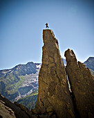 A rock climber stands on top of a pinnacle that he just completed in  the French Alps Mont Blanc, France