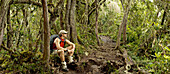 A young man rests after hiking in the jungle 13, 000ft. below Mt. Kilimanjaro's summit Tanzania