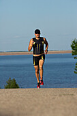 A male athelete running while training for a triathlon at a lake Lawrence, Kansas, USA