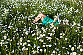 A young woman enjoys a quite moment reading a book in a field of wildflowers in Idaho Sandpoint, Idaho, USA