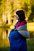 A woman wrapped in a sleeping bag enjoys the peace of Utah's Uinta Mountains Utah, USA