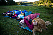 A group of women and a dog bedding down for the evening during a mountain sleep out Utah, USA