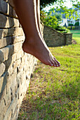 Young boy's legs hang off a stone wall Alpharetta, Georgia, USA