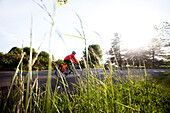 A young woman rides a bike around a park at sunset Seattle, Washington, USA
