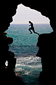 Young man silhouetted jumping into the Atlantic Ocean in the Hercules Cave near Tangier, Morocco, Tangier, Morocco