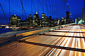 Cars pass over the Brooklyn Bridge with the New York City skyline in the background at dusk, New York New York City, New York, USA