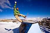 A male snowboarder in a green jacket jibs a quarter pipe at Snow Park in Wanaka, New Zealand Wanaka, Otago, New Zealand