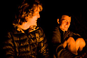 Two male climbers sit by a campfire in Joshua Tree National Park, California Joshua Tree, California, United States of America