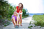 Two girls skateboard on a sidewalk connecting the Santa Rosa Sound with the Gulf of Mexico Pensacola Beach, Florida, United States