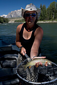 a young woman in a cowboy hat holding a fish net shows a cutthroat trout Jackson Hole, Wyoming, U.S.A.