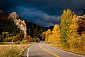 Highway with trees in fall color and stormy sky.  Walsenburg, Colorado Walsenburg, Colorado, United States