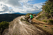 A young man rides his downhill mountain bike on Knapps Castle Trail, surrounded by beautiful scenery in Santa Barbara, CA Santa Barbara, CA, USA