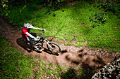 A young man rides his downhill mountain bike on a path surrounded by extremely lush green clovers Santa Barbara, CA, USA