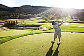 A golfer drives at sunset in Colorado Vail, Colorado, USA