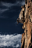 A young man rock climbing pulls the roof of a hard mixed climb in Colorado Vail, Colorado, USA
