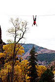 A young man does a bat hang from a slack line after walking the line Glenwood Springs, Colorado, USA