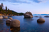 Evening light illuminates the granite boulders and calm waters of Lake Tahoe in the summer, NV Lake Tahoe, Nevada, USA