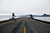 A couple jump on a long and lonesome road in West Wendover, Utah West Wendover, Utah, USA